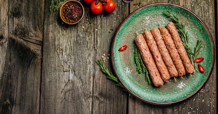 raw Lula kebab on skewers with spices on a white plate wooden background. Long banner format. top view.の写真素材