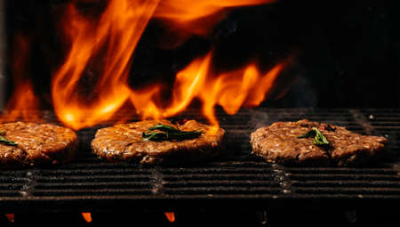 raw beef steak on a BBQ grill sizzling over flaming hot coals. steel grilled meat burger. Long...