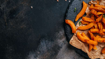 Homemade Fries Orange Sweet Potato with lime and herbs on dark background. Long banner format. top view.の写真素材