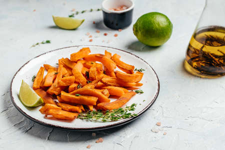 Sweet potato fries with lime and herbs on light background. top view.