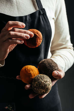 Female hands holding belper knolle cheese on a dark background, vertical image. place for text,