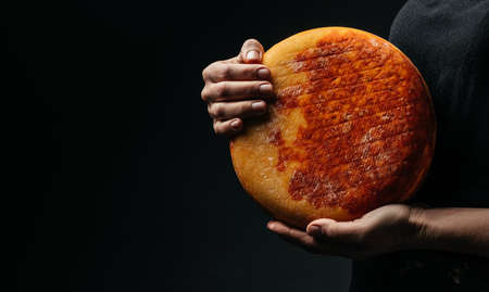 A cheesemaker controls the seasoning of the wheel hard cheese, delicious dairy product. Long banner...
