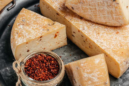 Pieces of pecorino cheese with dried tomatoes. Traditional italian hard cheese still life.
