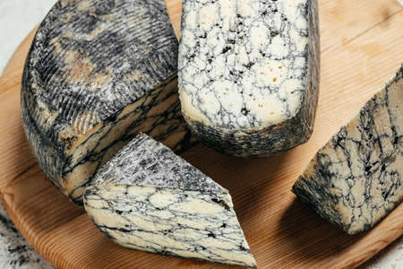 Asiago italian cheese with cuttlefish ink on a wooden board. Food recipe background. close up.