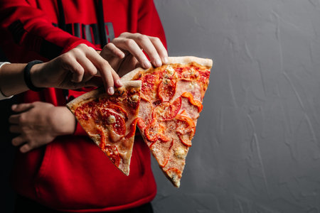 Two hands holding two slices of pizza. delicious pizza in hand.