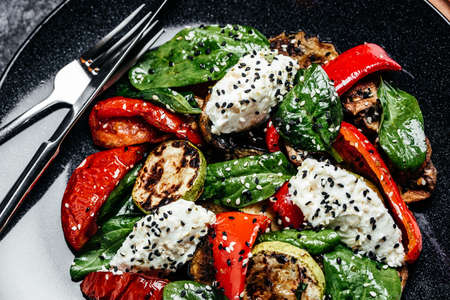 Delicious salad with roasted bell pepper, zucchini, eggplant with spinach leaves and feta cheese....