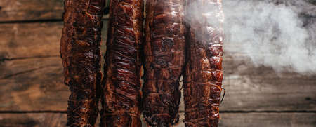 Traditional method of smoking meat in smoke. Smoked ham, bacon, pork neck and sausages in a...