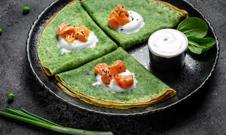 Green spinach crepes or pancakes with smoked salmon and soft cheese. banner, menu, recipe, place for text.の写真素材