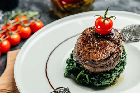 Tender lean medium rare beef fillet steak medallions with one sliced through to show the red meat with spinach, Restaurant menu, dieting, cookbook recipe,の写真素材