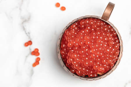 Red caviar in metal jar and a glas on white background. Gourmet food close up, appetizer, selective focus, place for text.の写真素材