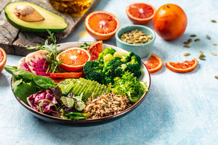 Vegan, detox Buddha bowl with vegetables, avocado, blood orange, broccoli, watermelon radish, spinach, quinoa, pumpkin seeds. Balanced food Delicious detox diet. top view.の写真素材
