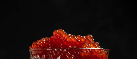 Red Caviar in a spoon. Caviar in bowl over black background. Close-up salmon caviar. Delicatessen. gourmet food. Texture of caviar. seafood.の写真素材