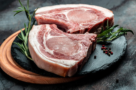 Organic Pork meat chop set with spices and rosemary and red pepper on black table. top view.の写真素材