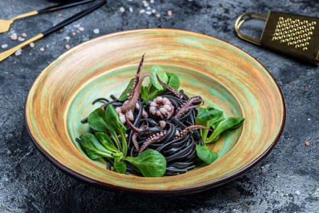 Squid ink spaghetti with seafood octopus, mussels and shrimps on dark background. Pasta of durum wheat semolina with squid ink. Restaurant menu, dieting, cookbook recipe top view,の写真素材