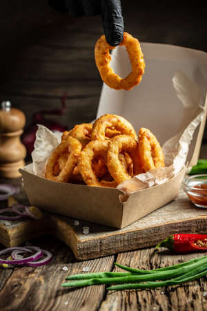fast food meal onion rings in paper box on wooden table. american food concept. banner, menu, recipe, place for text.の写真素材