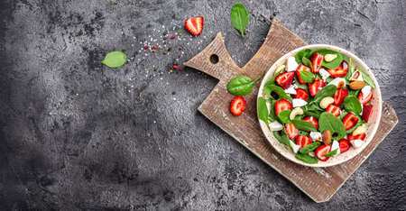 Diet menu. Healthy salad of fresh strawberry, spinach leaves, nuts and feta cheese, balsamic vinegar. Vegan food. Long banner format. top view.の写真素材