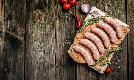 raw sausages with spices and rosemary on cutting board. cooking ingredients. natural healthy food concept. top view.の写真素材