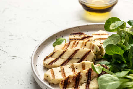 Grilled Halloumi cheese on white plate, Cyprus squeaky cheese. Long banner format. top view,の写真素材