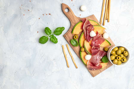 Fresh melon with prosciutto and basil. Antipasti, Traditional Spanish and Italian appetizer. Top view on white stone table, Long banner format. top view,の写真素材