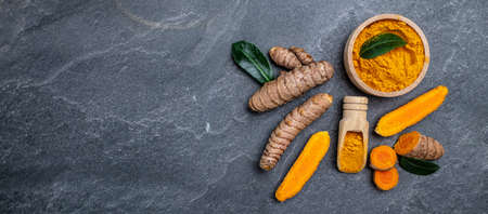 Turmeric powder and fresh turmeric. curcuma or curcumin on concrete background. Spice, natural...