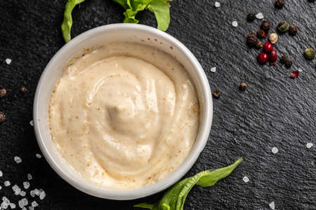 Bowl with garlic sauce on dark background. Food recipe background. close up,