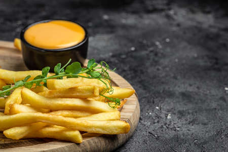 Fresh hot french fries with cheese sauce on a dark concrete background, Restaurant menu, dieting,...