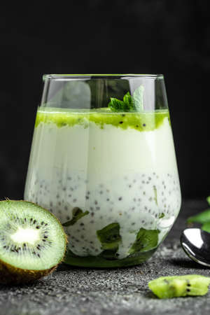 Healthy breakfast chia pudding with kiwi in glass jars on a white table. Clean eating, dieting, vegan food concept. vertical image.の写真素材