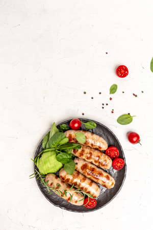 Grilled sausage with spinach, avocado and cherry tomato. hot barbecue dish. Keto paleo diet menu. Healthy fats, clean eating for weight loss. vertical image. top view. place for text.の写真素材