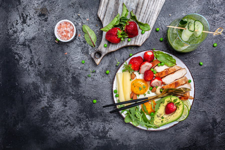 The ketogenic diet. Fried egg, avocado, strawberry, grilled chicken fillet, cheese, nuts and arugula, Low carb high fat breakfast, top view,の写真素材