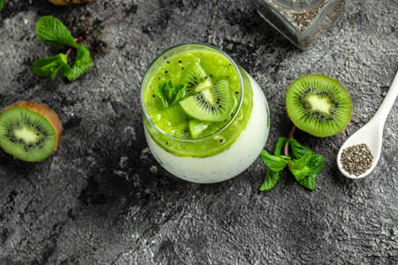 Healthy breakfast chia pudding with kiwi in glass jars on dark table. Clean eating, dieting, vegan food concept. banner, menu, recipe, place for text.の写真素材