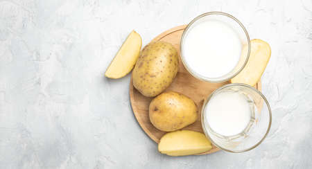vegan potato milk in glass and raw potato. Alternative plant based milk. superfood concept. Healthy, clean eating. Vegan or gluten free diet. top view.の写真素材
