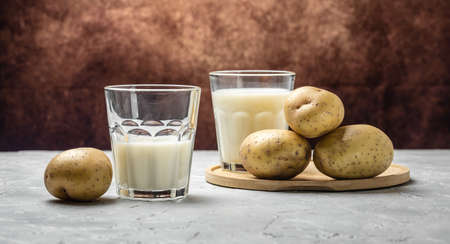 vegan potato milk in glass and raw potato. Alternative plant based milk. superfood concept. Healthy, clean eating. Vegan or gluten free diet. banner, menu, recipe place for text.の写真素材