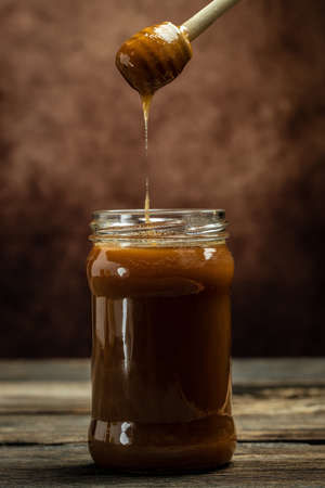 Sweet honey in glass jar and spoon on wooden background. Bees produce fresh, healthy, honey. Honey background. beekeeping concept,の写真素材