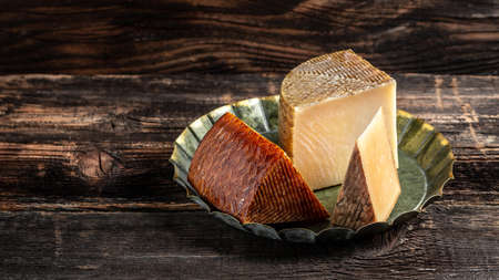 spanish manchego aged cheeses on rustic wooden table. banner, menu, recipe place for text.