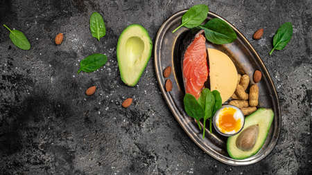 Keto diet food, salmon, avocado, cheese, egg, spinach and nuts. Ketogenic low carbs diet concept. Ingredients for healthy foods selection, place for text, top view,の写真素材