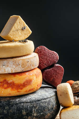 Various kind of cheese. head of handcrafted hard cheese on a dark background. vertical image. place for text.の写真素材
