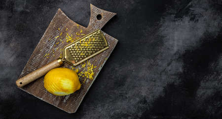 Peeling lemon rind to add zest to Mediterranean recipes. Grater peel and lemon zest on black...