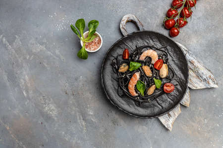 black spaghetti with prawn prawn and mussels seafood on gray background. Black spaghetti. delicious superfood. Long banner format. top view,の写真素材