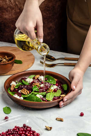 Woman mixing delicious superfood salad with beet fresh baby spinach, cheese, nuts, cranberries....
