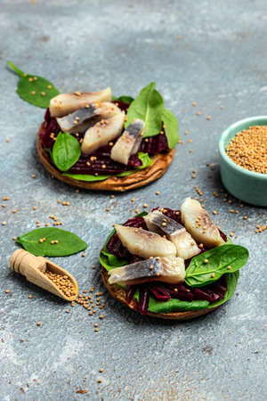 sandwich with slices of Atlantic herring fillet, beetroot salad, green spinach, onion, Scandinavian cuisine. Restaurant menu, dieting, cookbook recipe, vertical image. top view. place for text,の写真素材