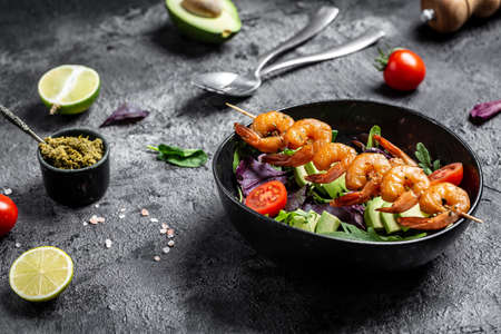 Vegetarian vegetable low carb lunch bowl with avocado, fresh salad, grilled shrimps and pesto sauce. Healthy diet seafood concept. top view.の写真素材