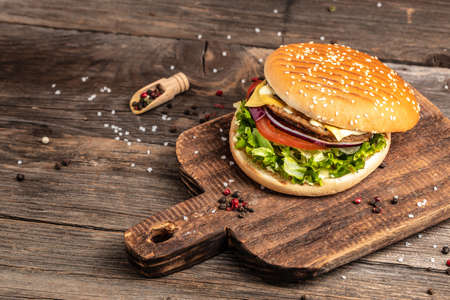 Homemade burger with grilled meat, vegetables, sauce on rustic wooden background. fast food and junk food concept.の写真素材