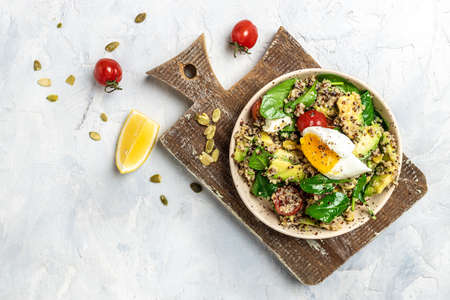 Keto diet plate quinoa, avocado, egg, tomatoes, spinach and sunflower seeds on light background. Healthy food, ketogenic diet, diet lunch concept, place for text, top view.の写真素材