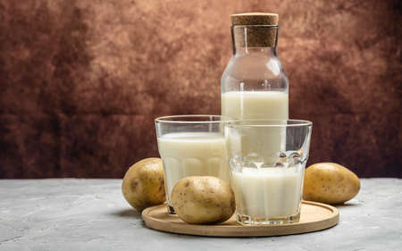 vegan potato milk in glass and raw potato. Alternative plant based milk. superfood concept. Healthy, clean eating. Vegan or gluten free diet. banner, menu, recipe place for text.の写真素材