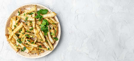 Roasted Parsnips on light Background. side dish on plate. Delicious vegetarian breakfast or snack on a light background, Clean eating, dieting, vegan food concept. Long banner format. top view.の写真素材