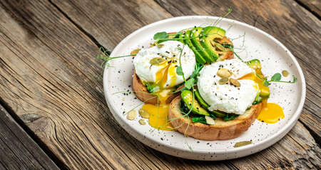 Sandwich with spinach, avocado, egg and pumpkin seeds on the wooden table, Healthy food, keto diet,...