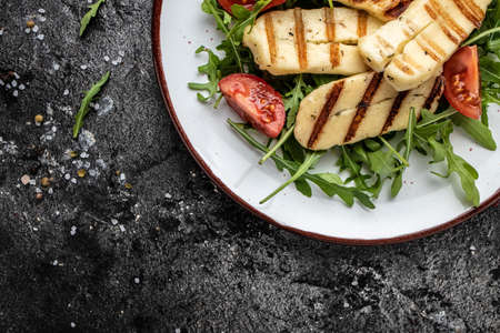 Grilled Halloumi cheese salad on white plate, Cyprus squeaky cheese. Long banner format. top view,の写真素材