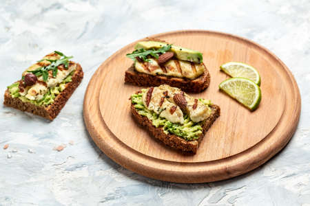Grilled Halloumi cheese, avocado guacamole, arugula on roasted bread. Food recipe background. close...
