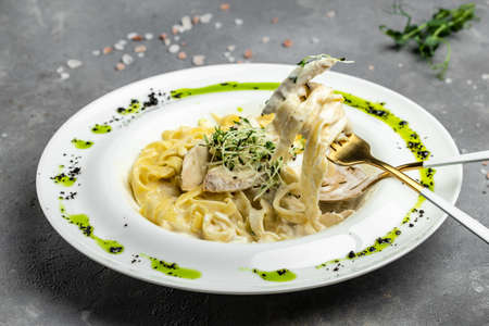 Fettuccine alfredo in a creamy sauce with chicken, parmesan on white plate. Pasta alfredo with...