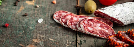 Fuet Salami cut in slices on a wooden background. Traditional Spanish sausage. Long banner format. top view.の写真素材